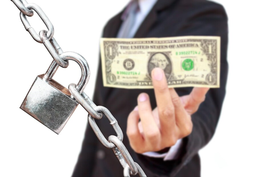 CEO con un dolar en su mano mostrándolo directamente al frente, el cual está protegido por una cadena y candado